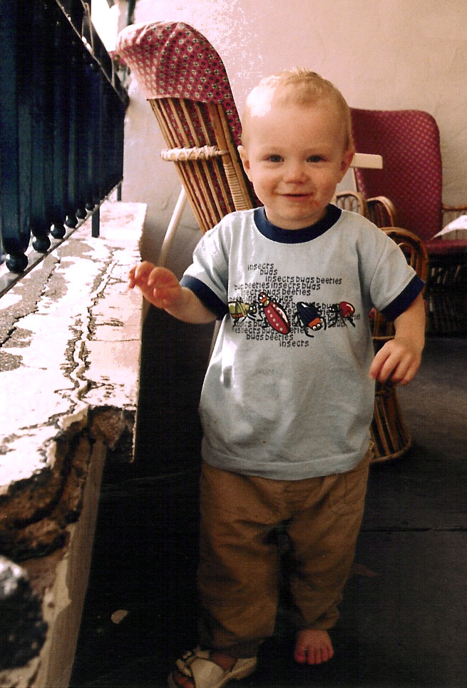 A shoeless and grinning Mateo with pizza on the face